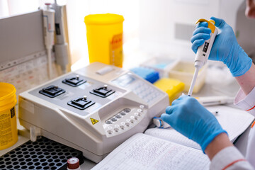 Modern robotical machine for centrifuge blood and urine testing. Hands in blue latex gloves put...