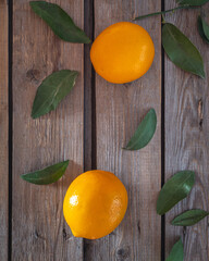 Lemons and green leaves on a wooden unpainted table top view