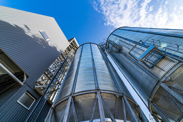 Metal grain elevators on modern factory. Crop storage in factory. Selective focus on steel constructions and technique.