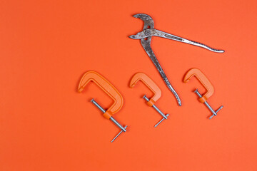 Monkey wrench and clamp, clamps on an orange background. compress, repair, construction.