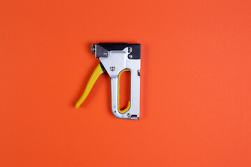 furniture stapler on an orange background