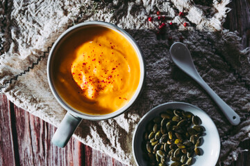 Soupe de courge et carottes aux baies roses dans un bol sur une table de cuisine en bois