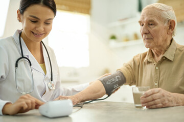 Easy-going doctor using a manometer while examining her aged patient