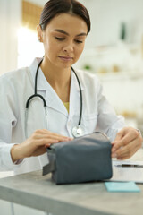 Professional doctor packing up her medical equipment into bag