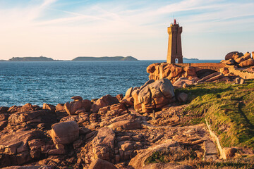 Pink Granite Coast in Brittany near Ploumanach, France.Ploumanach Mean Ruz lighthouse red sunset in...
