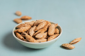 Pile of Almond nuts in a bowl on a light blue background