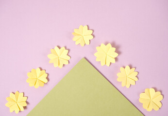 Yellow paper spring origami folded flowers on a green and lavender paper background.  Spring time Easter flat lay with copy space