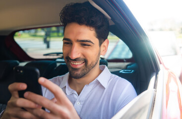 Businessman using mobile phone in car.