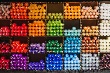 Many different colored candles on a shelf