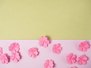 Pink paper cherry blossom origami flowers on a green and lavender paper background.  Spring time Easter flat lay with copy space