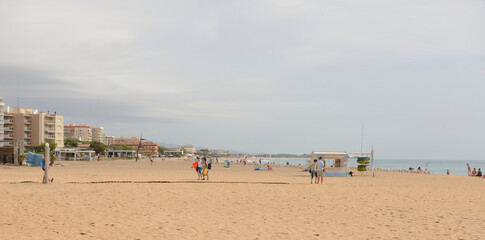 Fototapeta premium Tourists walking and sunbathing on the beach