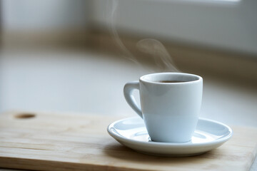 A white coffee cup with a transparent haze of steam over the hot drink. Selective focus.