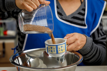 Agregando azúcar en recipiente para preparar un postre. concepto de repostería en casa