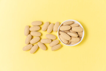 Vitamin C tablet on yellow background. Selective focus.