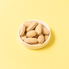 Vitamin C tablet on yellow background. Selective focus.