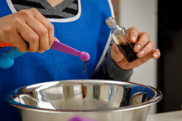 Agregando vainilla con una cuchara medidora a un recipiente, para preparar un panque de plátano. Concepto de repostería en casa