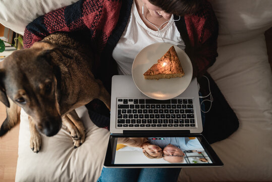 Daughter and senior parents doing video call birthday party at home with dog - Coronavirus lockdown concept - Focus on cake