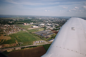 Fototapeta na wymiar view from the window of a small plane on the city and fields, landscape