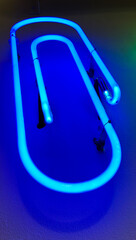 Blue office clip shaped neon light installed on white wall