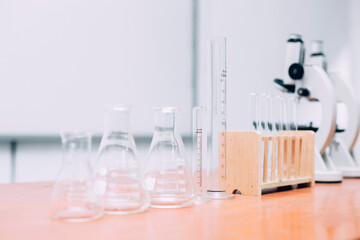 Different empty laboratory beakers and glassware with microscope on the table in laboratory