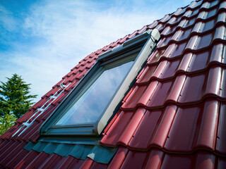 Close up view from outside mansard window.Skylight attic window in roof of red tiles,attractive...