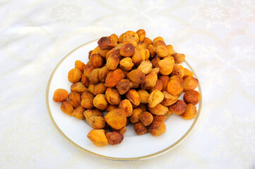 Pile of dried apricots, uryuk, placed on a plate on a cream coloured tablecloth