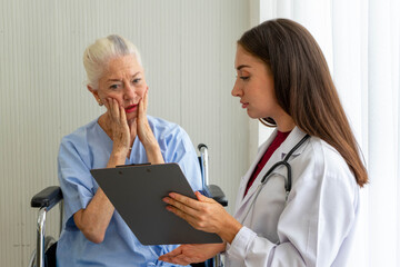 Caucasian old senior depressed upset woman patient on wheelchair talking to medical doctor with stethoscope  in hospital 