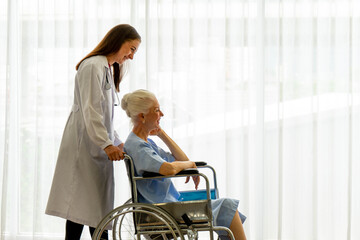 Caucasian old senior depressed upset woman patient on wheelchair talking to medical doctor with stethoscope  in hospital 