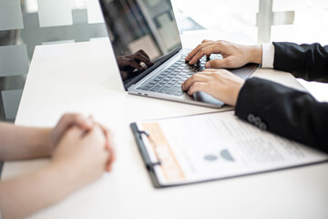 Manager typing on laptop keyboard while interviewing with female job applicants.