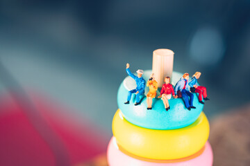 Miniature people sitting on colorful wooden block using as business and social concept