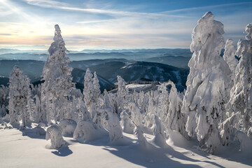 Early morning in the mountains on a cold winter day. Sun rises above the distant horizon. Trees...