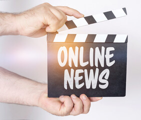 On a white background, a man holds a clapperboard in his hands on which it is written - ONLINE NEWS