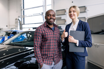 African man standing with a girl in a car dealership