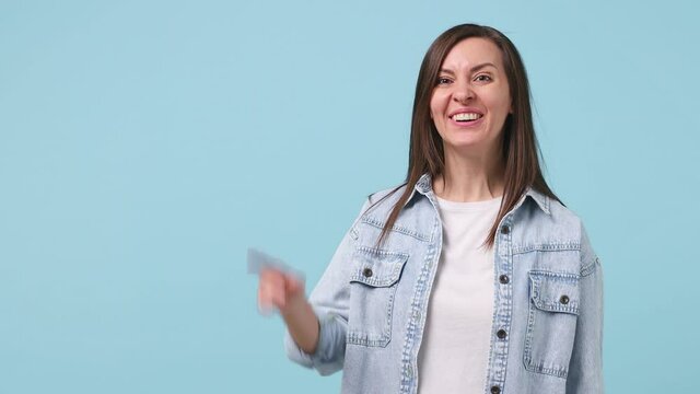Surprised shocked excited fun young woman 30s years old in denim jacket white t-shirt point index finger aside scream in megaphone announces discounts sale Hurry up isolated on pastel blue background