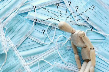 image of wooden dummy with worried stressed thoughts. over protective face mask background. anxiety and overload during covid-19 coronavirus pandemic