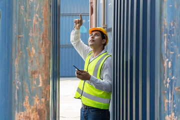 The supervisor put on a helmet. The engineer raised his hand to inspect the work, looking over the container at the container yard. Logistics concept 