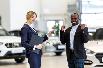 African man buying a car at a car dealership. The girl passes the keys to the new purchased car