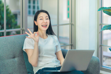 Happy Woman working on laptop in livingroom at home with ralaxing and smile during quarantine...