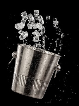 Ice cubes up from a metal cold champagne bucket on black background