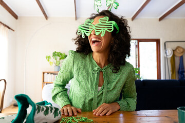 Caucasian woman dressed in green with shamrock glasses for st patrick's day laughing