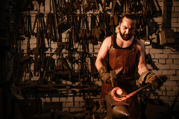 Fototapeta na wymiar The blacksmith's hammer hits the hot iron in the forge