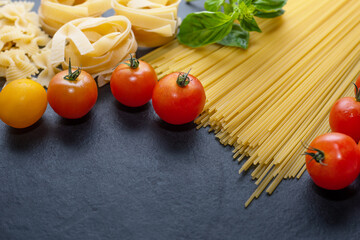 Mixed dried pasta selection on wooden background. composition of healthy food ingredients isolated on black stone background, top view, Flat lay.