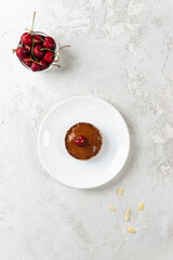 Chocolate cake with cherries on a plate. Raw dessert, healthy food. Sugar, gluten and lactose free. Vertical orientation, top view.