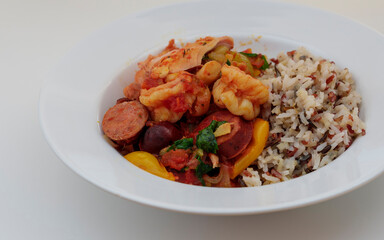 Jambalaya with chicken, shrimp, sausage, and rice in tomato sauce served on a white shallow bowl