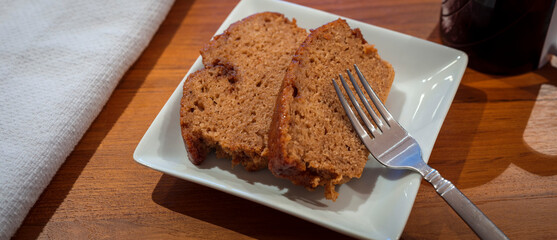 Two Slices of Apple Cider Donut Loaf Cake Served on Small White Square Plate with Stainless Fork - Powered by Adobe