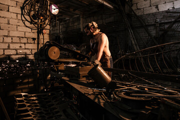 Fototapeta na wymiar Blacksmith sawing iron in the forge. Hard male labor