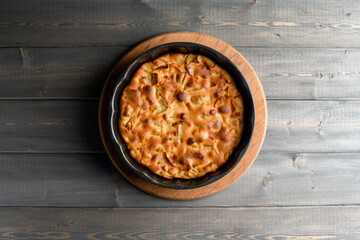 Apple pie in a round shape on a wooden background. Apple charlotte