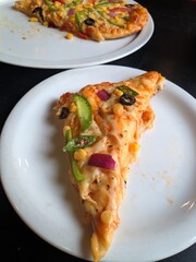 Vegetarian pizza slice over a white plate on black table