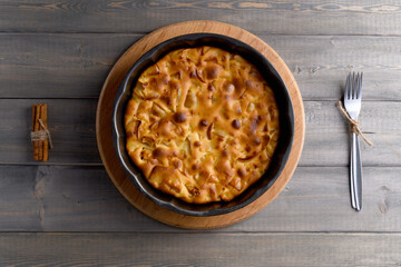 Apple pie in a round shape on a wooden background. Apple charlotte