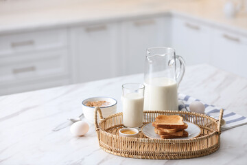 Tasty breakfast with toasted bread and milk on white marble table in kitchen